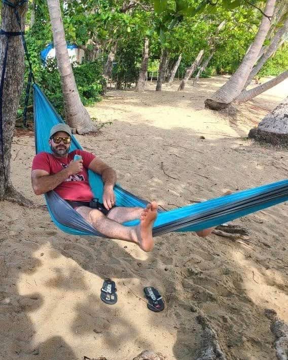 Caleb relaxing in a hammock between palm trees on the beach
