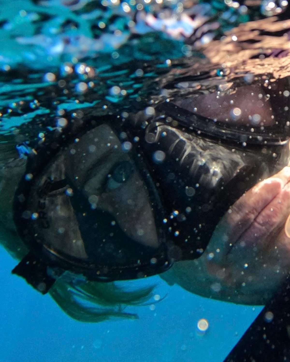 Shawn at the water's surface in her snorkel mask, sunlight rippling across her face