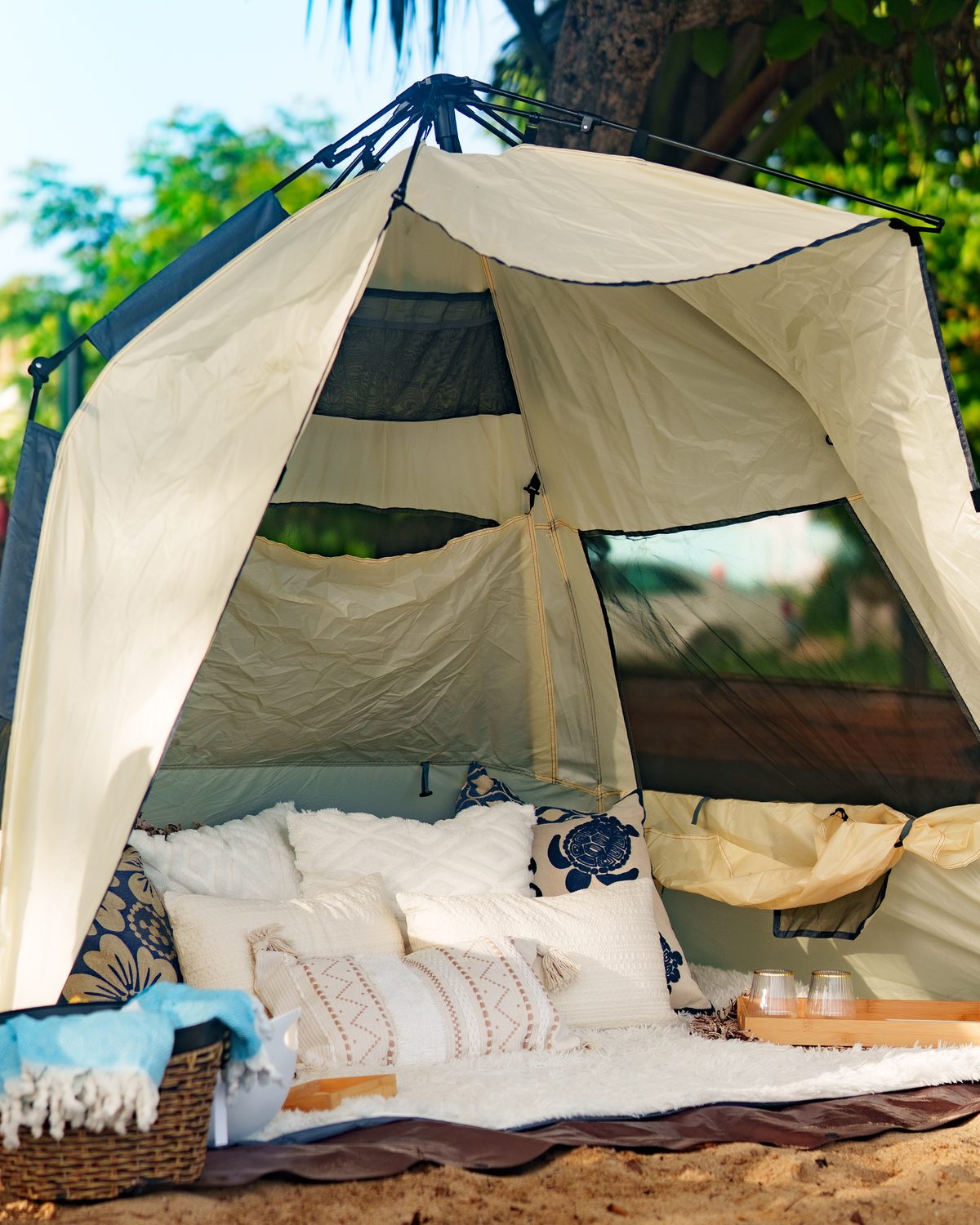 The luxury tent set up on the sand — pillows, throws, and trays ready for guests