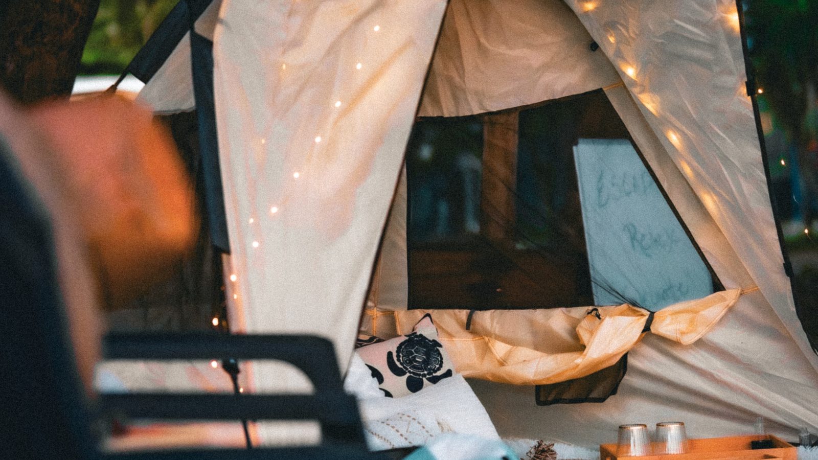 The luxury tent glowing with string lights on the sand at dusk