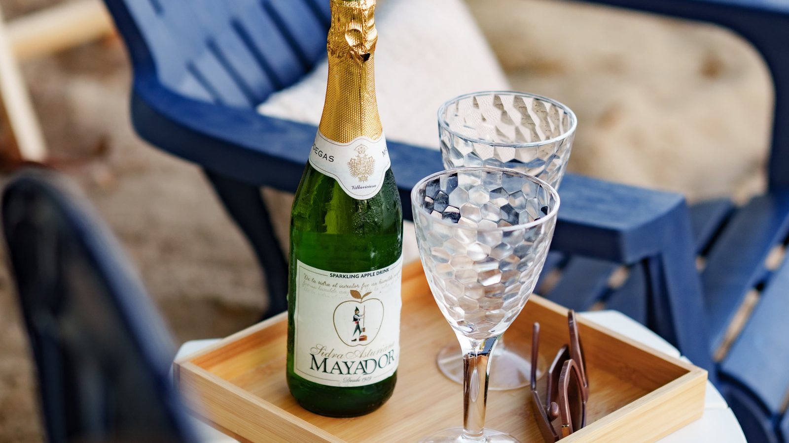 A tray with a sparkling bottle and glasses between two beach chairs